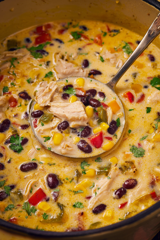 A spoon is in a bowl of chicken tortilla soup.