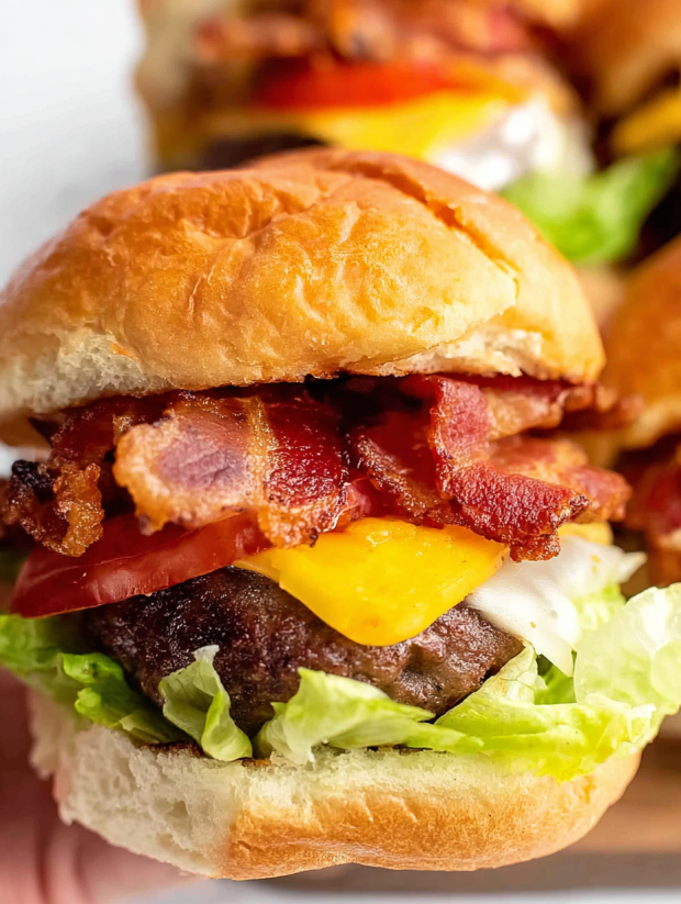 Bacon cheeseburger sliders with lettuce and tomato.