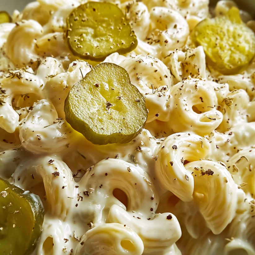 A dish of macaroni with pickles on top.