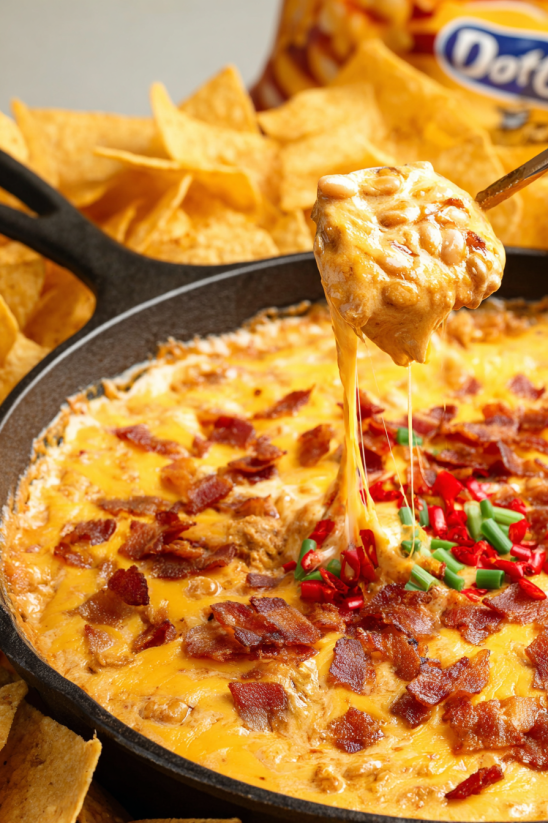A spoon is dipping into a bowl of Frito chili cheese dip.
