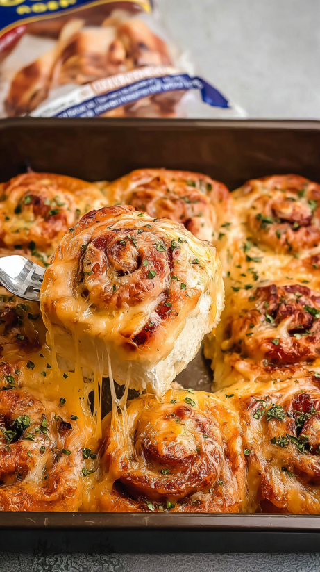 A fork is stuck in a piece of ham and cheese pizza rolls.