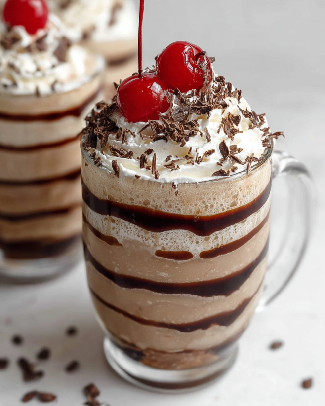 A glass of frozen mudslide with chocolate and cherries.