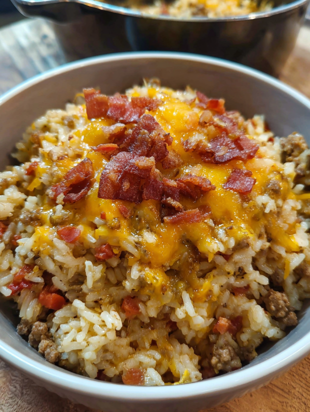 A bowl of rice with bacon and cheese on top.