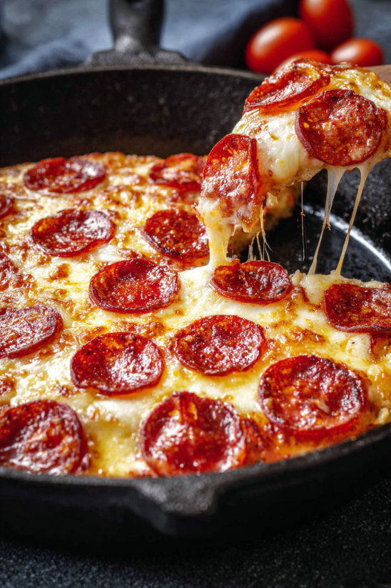 A slice of pepperoni pizza being dipped into a pan.