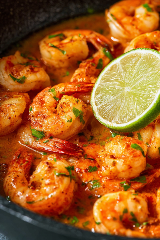 A bowl of shrimp with a slice of lime on top.