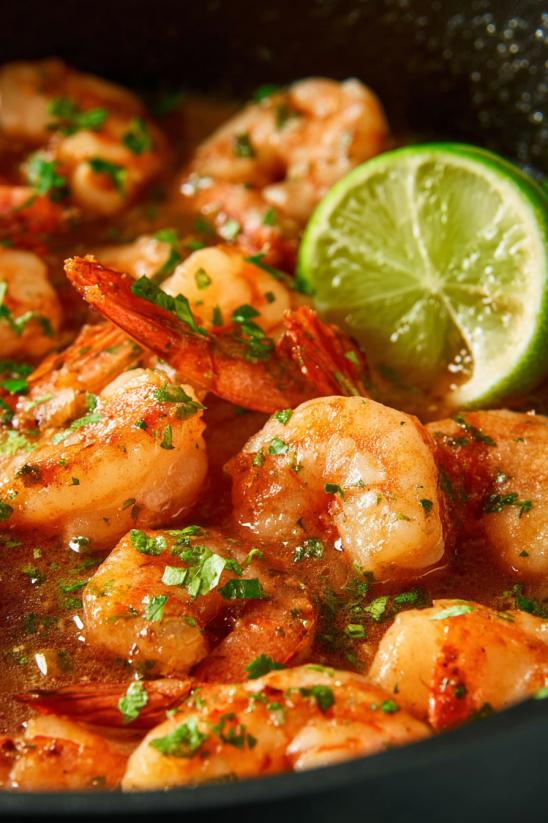 A plate of shrimp with lime wedges on top.