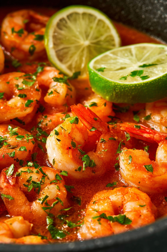 A plate of shrimp with limes and parsley.