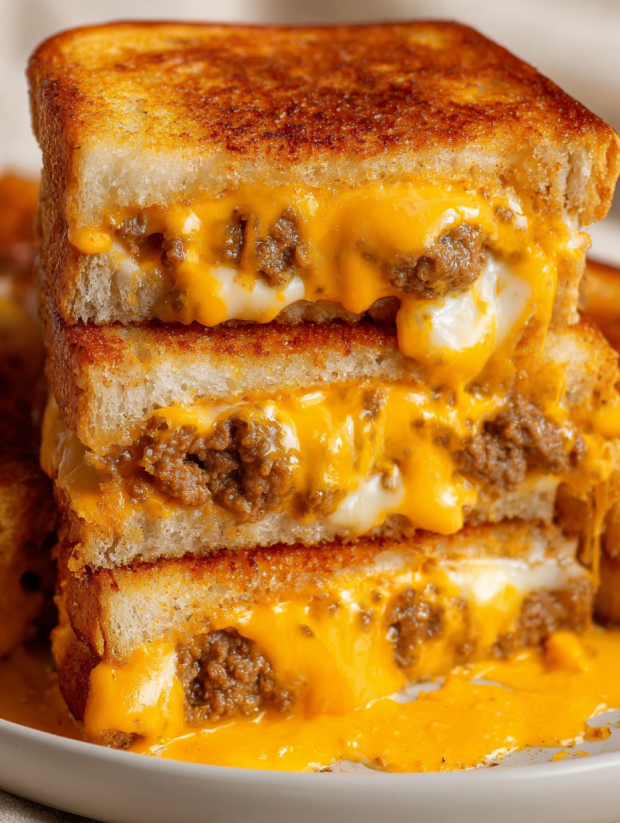 A stack of grilled cheese sandwiches with sausage and egg.