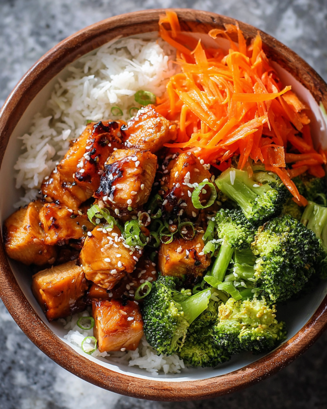 A bowl of food with broccoli, carrots, and chicken.