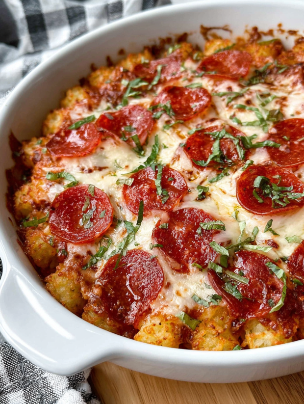 A white bowl filled with a pepperoni pizza tater tot casserole.