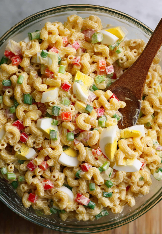 A close up of a macaroni salad with eggs and peppers.