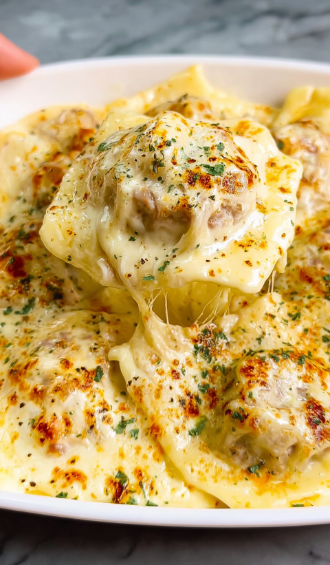A close up of a piece of sausage Alfredo Ravioli Lasagna.