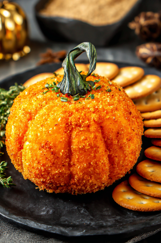 A pumpkin cheese ball is on a plate.