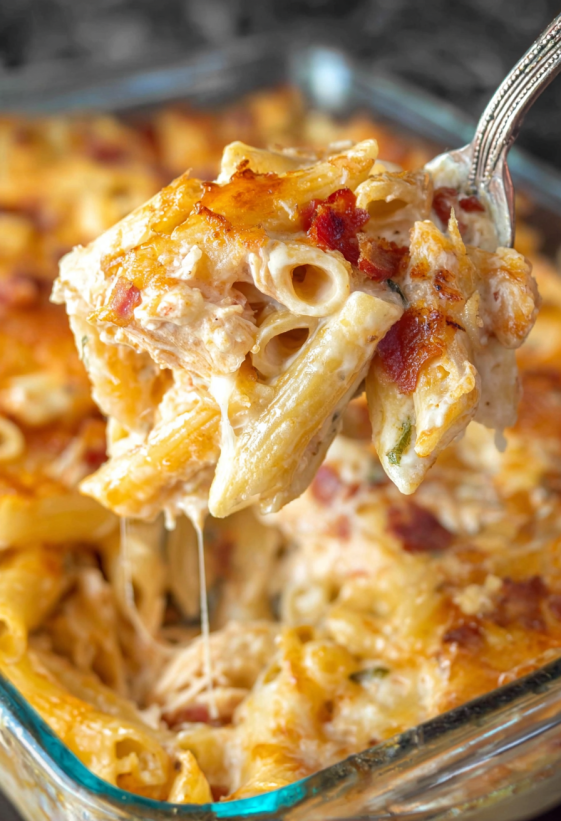 A fork is holding a piece of buffalo chicken mac and cheese.