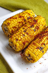 A plate of corn on the cob with jerk rubbed on it.