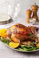 A roasted turkey with oranges and green beans.